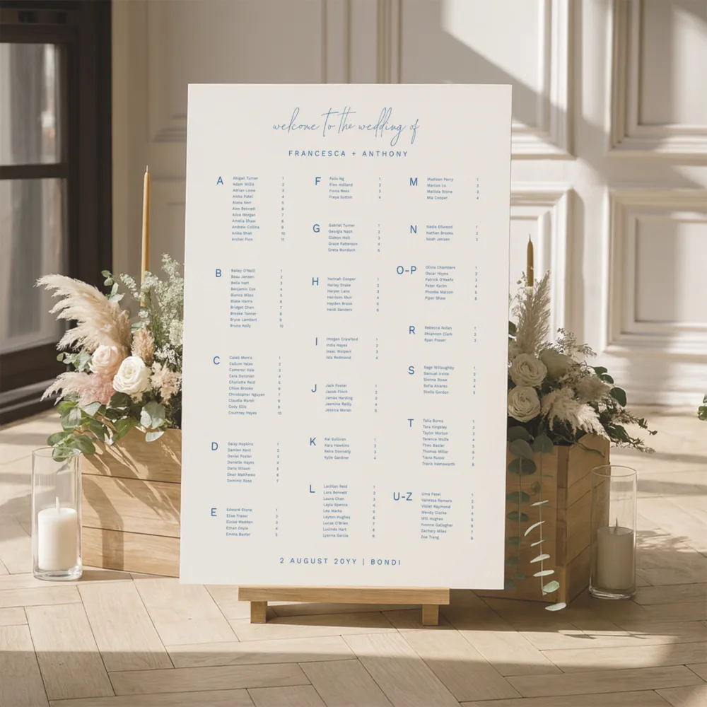 Modern alphabetical wedding seating chart featuring a mix of script and serif fonts. The Bondi design is shown on a wooden block stand with dried pampas grass, perfect for a coastal or beach-themed Australian wedding.