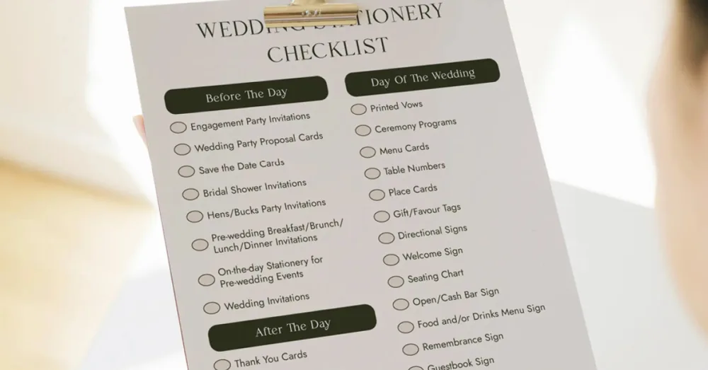 A printed A4 wedding stationery checklist on a wooden clipboard