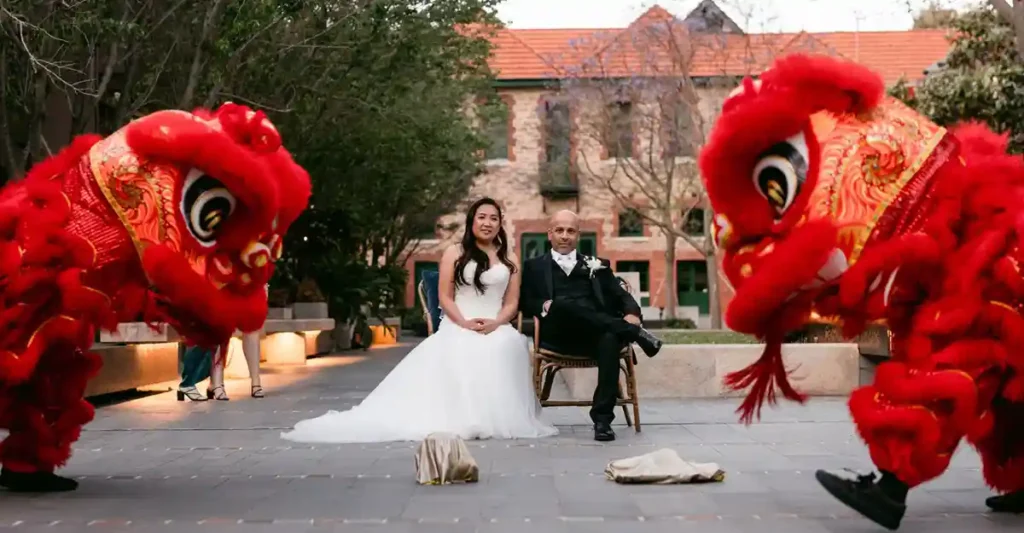 A man and woman sitting in chairs in front of a building on their wedding day