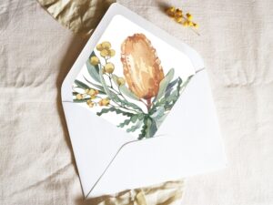 White envelope with a printed liner showing a painted banksia bouquet.