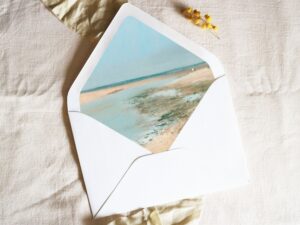 White envelope with a printed liner showing a beach scene.