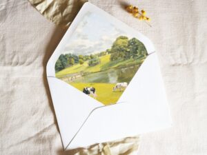 White envelope with a printed liner showing a farm pasture landscape.