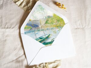 White envelope with a printed liner showing a painted river landscape with fishing boats.