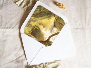 White envelope with a printed liner showing a painted forest landscape with a waterfall.