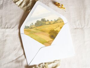 White envelope with a printed liner showing a farm pasture landscape.