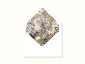 White envelope with a printed liner showing painted small purple and white flowers.