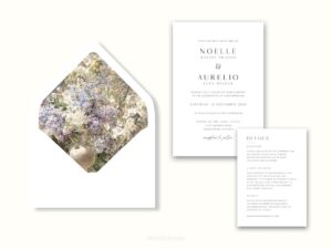 White envelope with a printed liner showing painted small purple and white flowers next to wedding invitations.