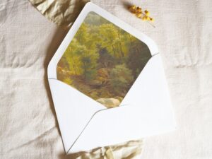 White envelope with a printed liner showing a painted forest landscape.