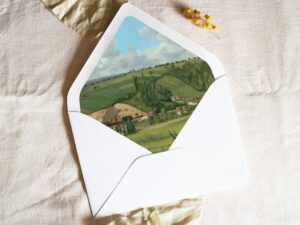 White envelope with a printed liner showing a painted countryside landscape.