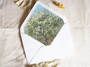 White envelope with a printed liner showing a painted orchard tree in bloom.