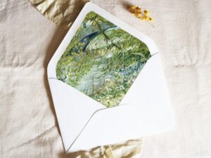 White envelope with a printed liner showing a painted green forest river landscape.