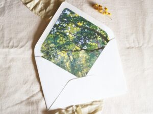 White envelope with a printed liner showing painted forest scene.