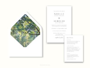 White envelope with a printed liner showing painted forest scene next to wedding invitations.