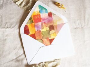 White envelope with a printed liner showing a painted cube pattern.