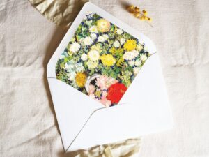 White envelope with a printed liner showing a painting of white and yellow flowers.