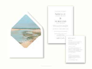 White envelope with a printed liner showing a beach scene next to wedding invitations.