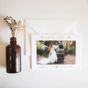 A wedding thank you card on a table next to flowers