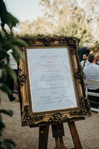 A wedding menu in a gold frame on an easel