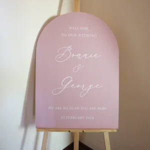 An arch-shaped wedding welcome sign on an easel