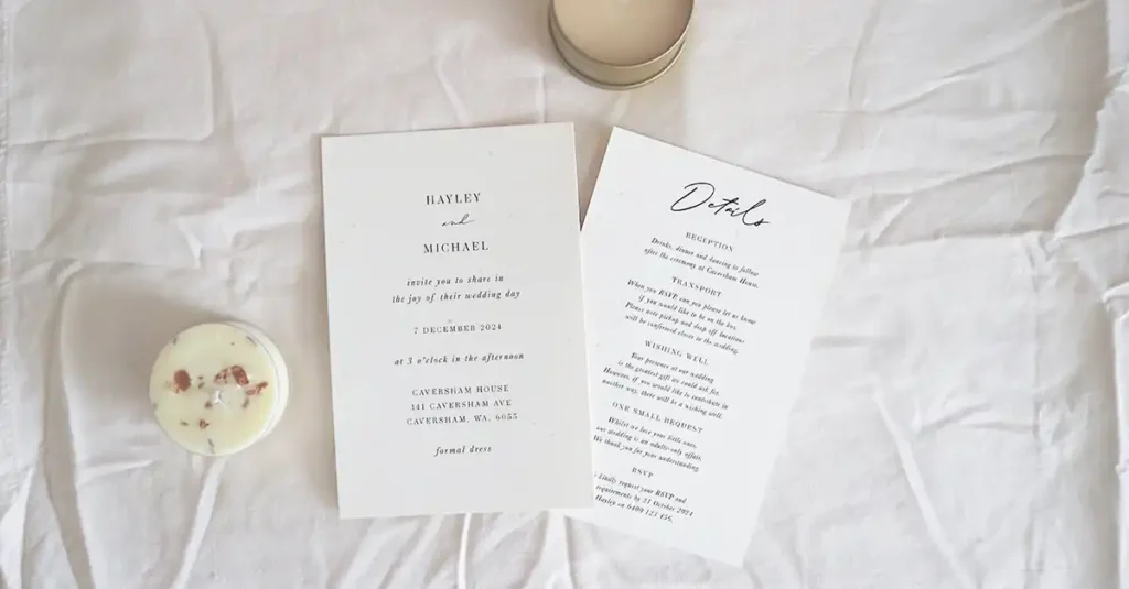 Two invitation cards sitting side by side on a white tablecloth