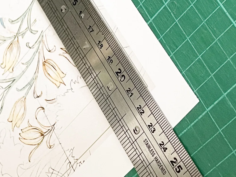 Metal ruler aligned to cutting guideline on printed envelope liner template