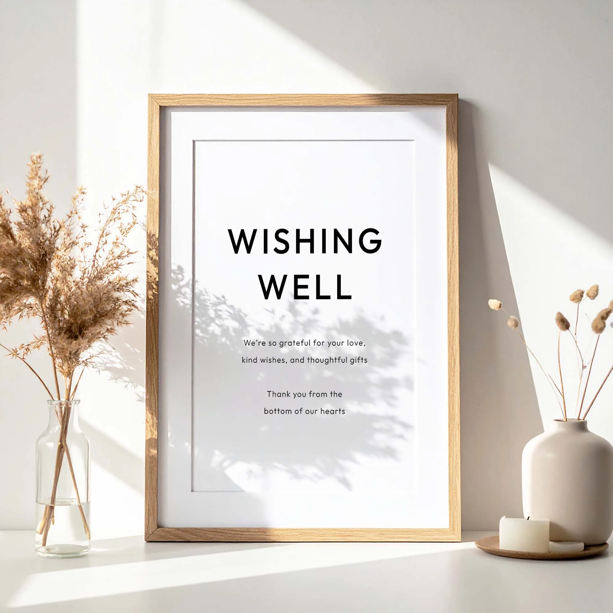A printable wishing well sign with modern typography in a wooden frame on a wedding table.