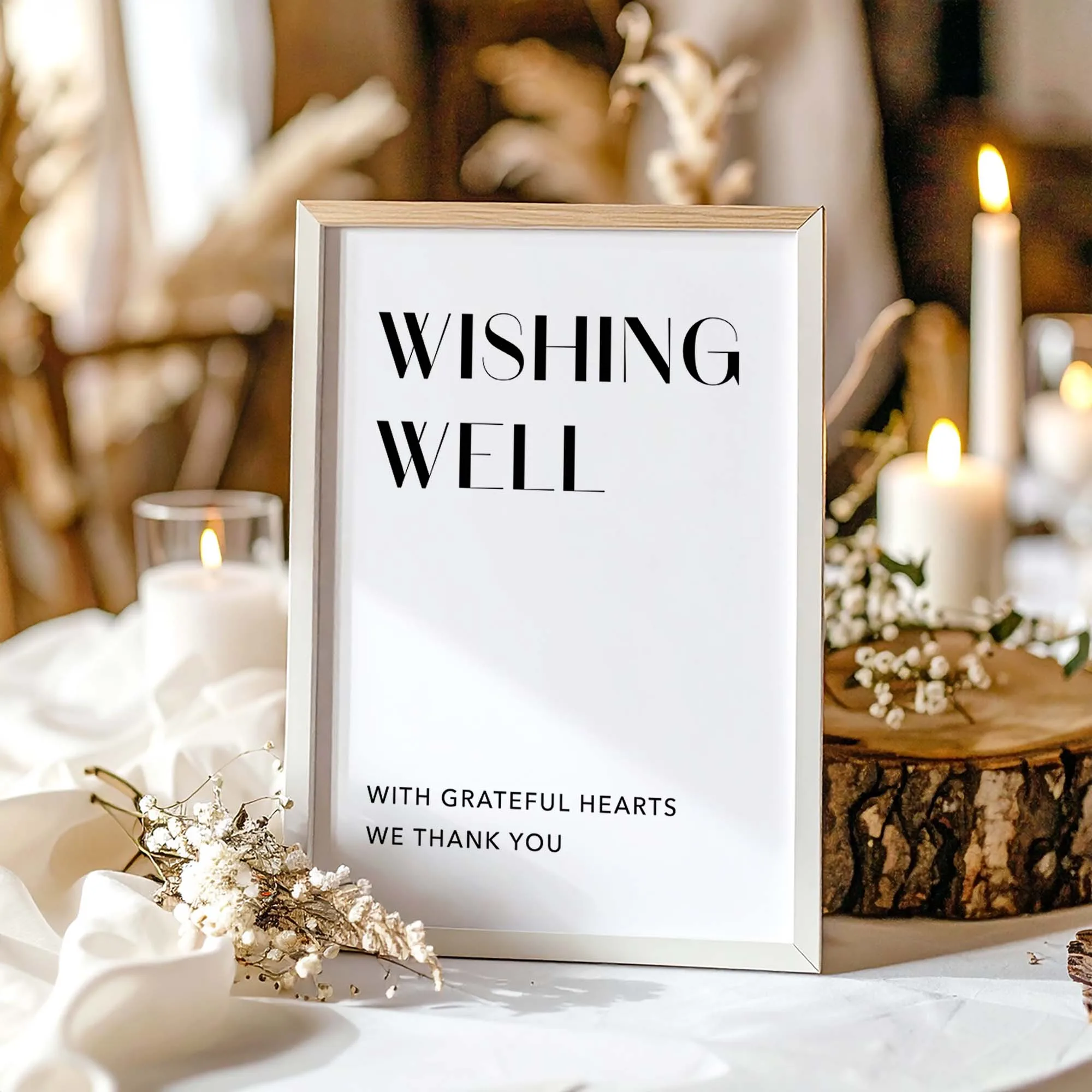 A printable wishing well sign with modern typography in a white frame on a wedding table.