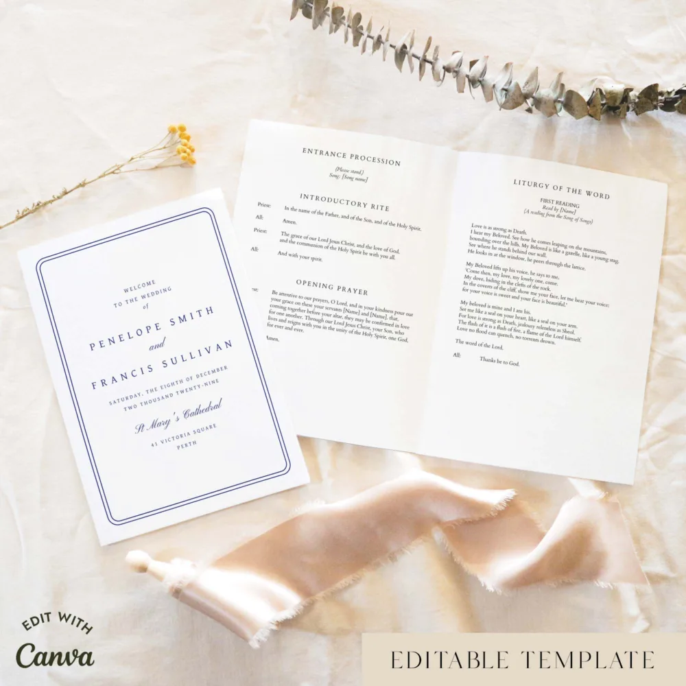 Classic blue A5 Catholic wedding ceremony booklet shown open with the cover beside it, styled on light fabric with dried florals and a soft ribbon.