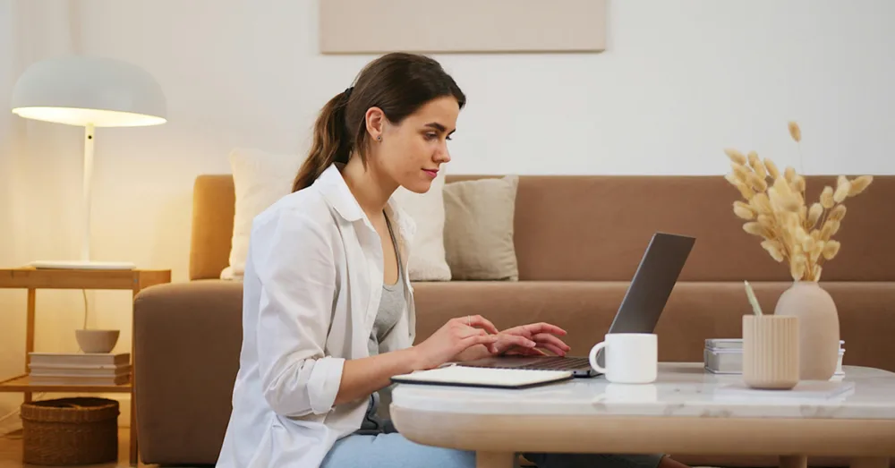 A woman sitting on the floor using a laptop on a coffee table