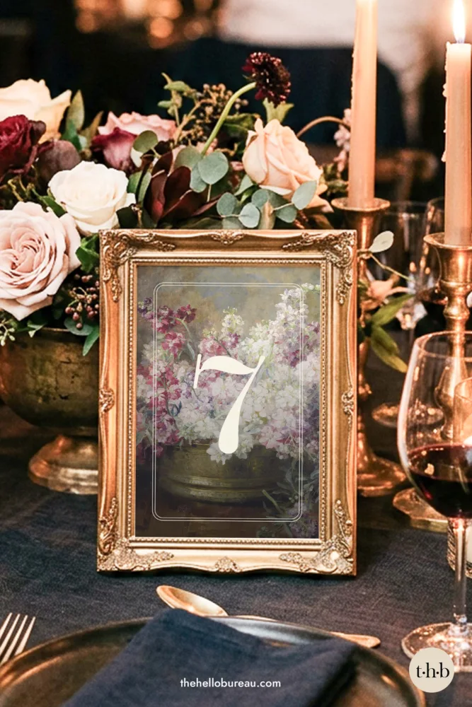 Blumen fine art table number in an ornate gold frame on a candlelit wedding table with roses and tapered candles