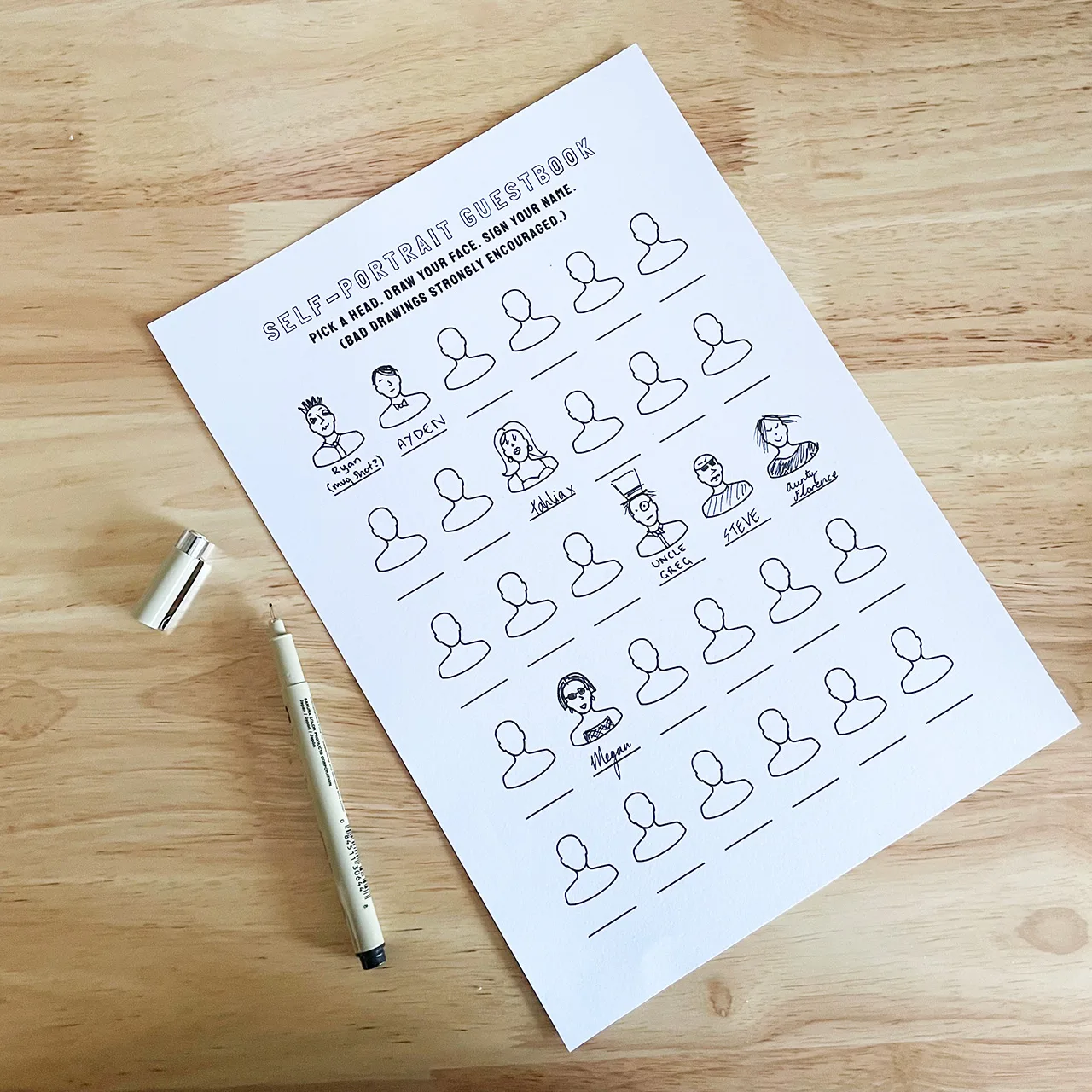 Draw Your Face Guestbook template partially filled in with hand-drawn self-portraits and signed names, next to a fine liner pen on a wooden table