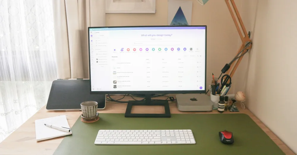 A desktop computer on a wooden desk with a green desk mat.