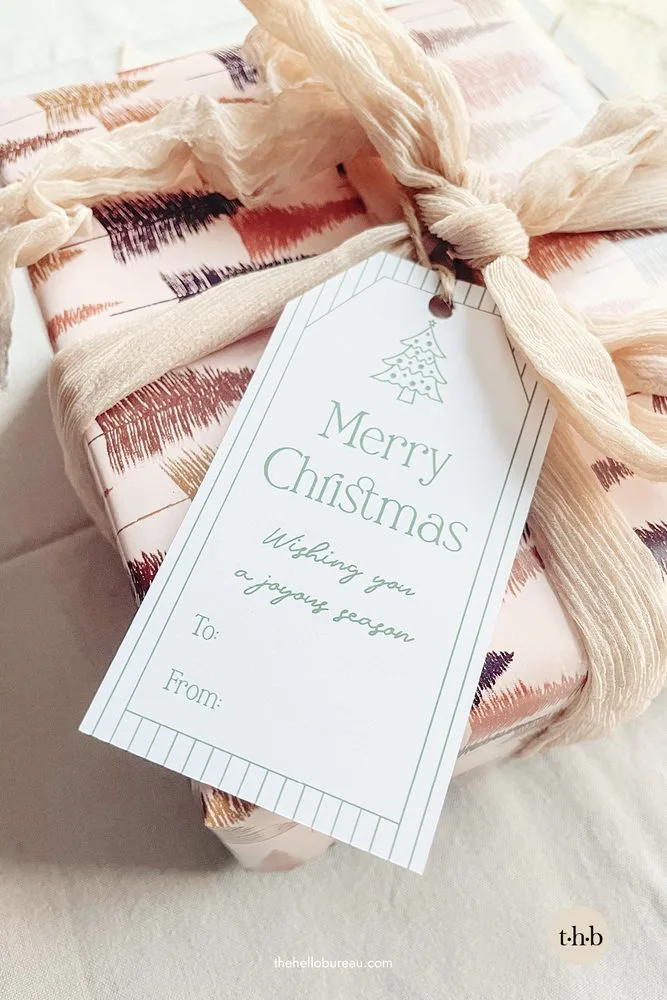 Modern classic Christmas gift tag tied to a wrapped present with ribbon